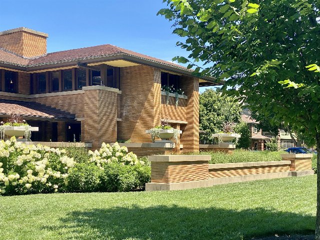 a building surrounded by neat landscaping with flowering shrubs, some trees, and a monoculture lawn