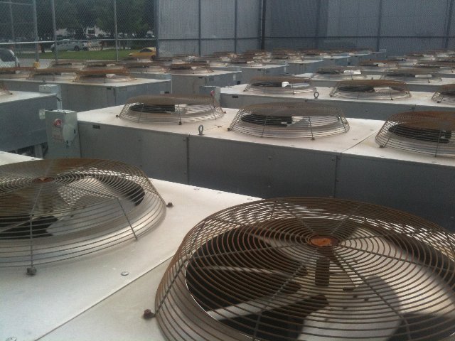 Many large fans under grates, facing up, in metal boxes, part of the HVAC system of a large building.